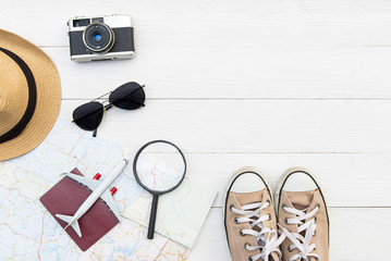 Tourist summer travel planning trip concept on map with passport, airplane, camera, hat and sunglasses, old wood white background. Travel and Summer Concept