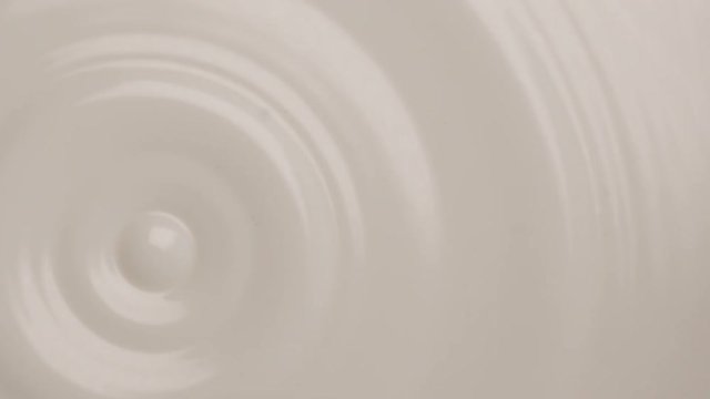 Macro shot of beauty cream dropping into white milky background. Macro shot of milk dropping in super slow motion