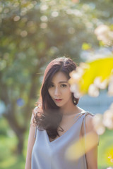 Portrait of beautiful asian woman  look at camera  outdoors in a park. Pretty Thai girl with flower.