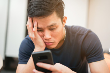 close up asian man feeling bored and sleepy when playing smartphone , lifestyle people concept