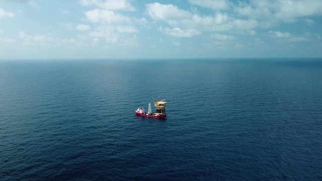An aerial view from a drone of a soil boring boat (a geotechnical drilling cum analogue survey vessel) close to a oil platform
