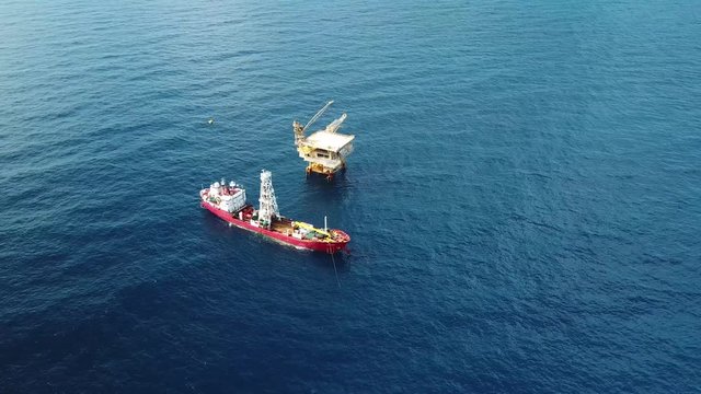 An aerial view from a drone of a soil boring boat (a geotechnical drilling cum analogue survey vessel) close to a oil platform
