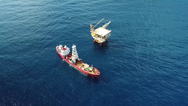 An aerial view from a drone of a soil boring boat (a geotechnical drilling cum analogue survey vessel) close to a oil platform
