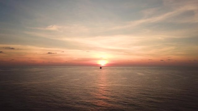 Aerial view from a drone of a small offshore platform in the middle of the ocean during sunset
