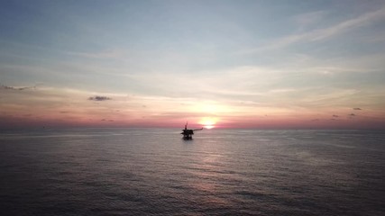 Aerial view from a drone of a small offshore platform in the middle of the ocean during sunset

