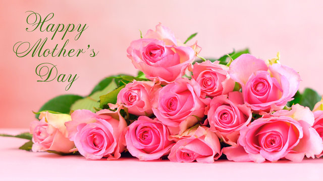 Pink roses on pink wood table, Happy Mother's Day background closeup with greeting message text.