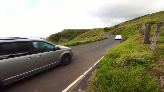 tourist car driving along the coastline on Road to Hana in Maui Hawaii. Beautiful green landscape and nature.