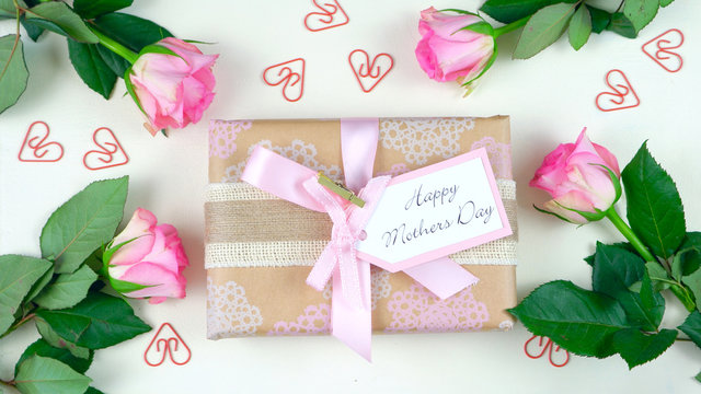Happy Mother's Day overhead with gift and pink roses on white wood table background
