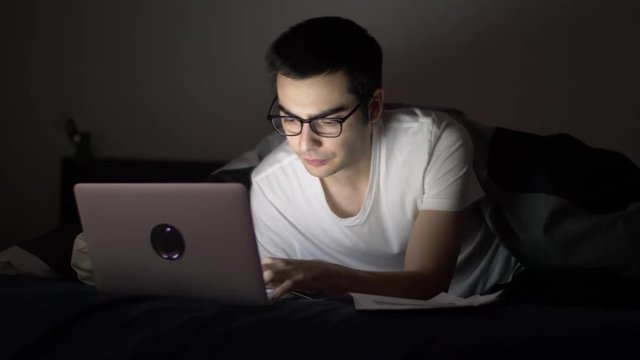Man at night in his bed with a laptop working on a project late