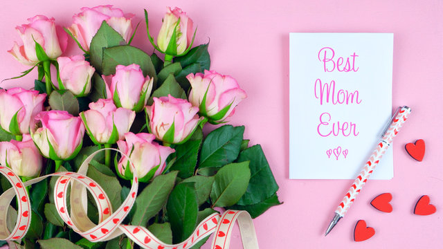 Happy Mother's Day overhead with roses, Best Mom Ever card and gift on pink wood table.