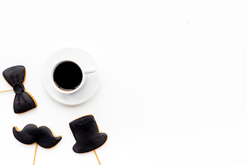 Father's Day celebration concept. Monochrome. Cookies in shape of moustache, hat, bow tie near coffee on white background top view copy space