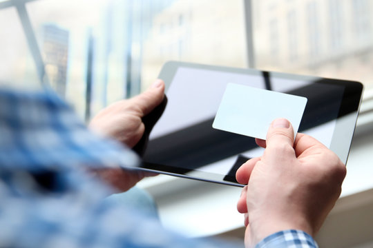 business man entering data of a credit card . On-line shopping on the internet using a digital tablet
