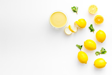 Lemon curd in bowl among lemons on white background top view copy space