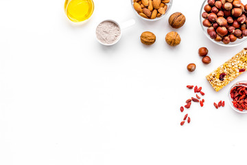 Make hearty granola bars with oatmeal, nuts, honey and berries. White background top view copy space