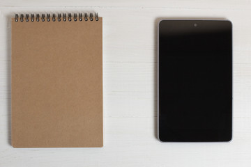 Pen of a natural wood smartphone and notebook on a white table.