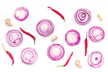 Red onion rings as seasoning. Onion near chili peper, garlic on white background top view pattern