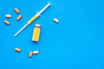 Medical therapy. Syringe, bottle with drug, pills on blue background top view copy space