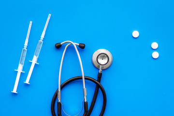 Medical examination and treatment concept. Stethoscope, syringe, pills on blue background top view