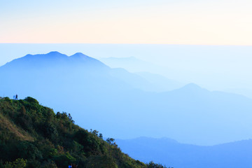 Hiker stands alone on the mountain peak at dusk.