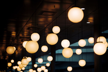Many round chandeliers and lamps under ceiling.