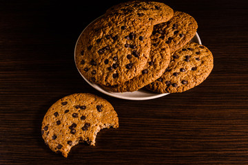 Plate with chocolate chip cookies on a dark wooden table