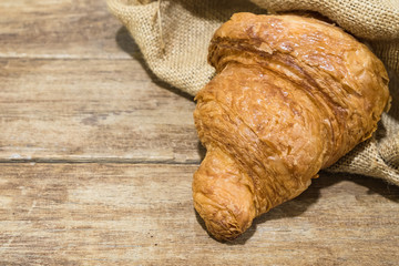 fresh butter croissant in gunny sack cloth on wooden table