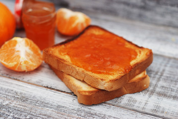 Fresh Toasts with Homemade Orange Jam on Gray Plate over Wooden Background.