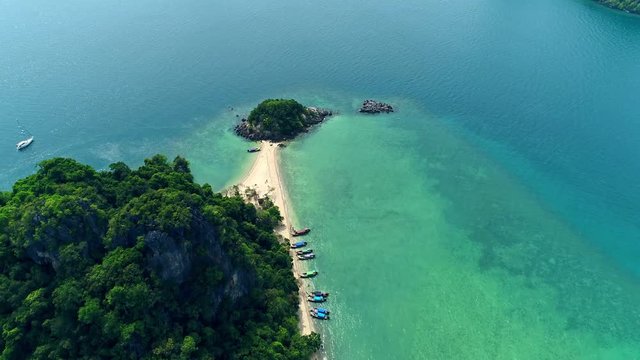 AERIAL. Top view of small isolated tropical island with white sandy beach and blue transparent water and coral reefs. Aerial shooting, speedboats, longtail boats, Khai Nok island, Phuket, Thailand.
