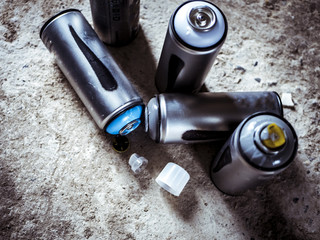 used graffiti spray paint cans on the ground