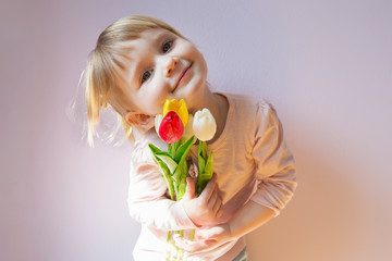Sweet happy little blond-haired girl holding a bouquet of colorf
