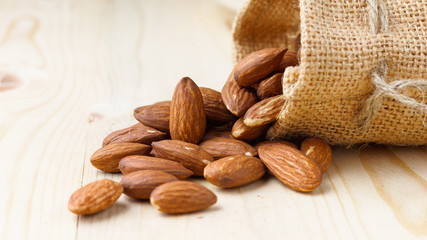Roasted almonds in a sack on wooden table with copy space