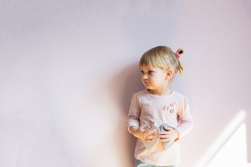 A serious little girl. A little girl with blond hair holds two w