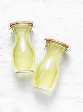 Homemade chicken broth stock in glass bottles. Canned preserved ingredient for cooking lunch on light background, top view