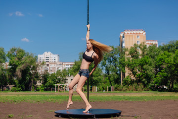 Fit attractive girl dancing near portable pole at summer day © Smile