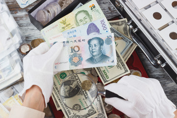 Hands in the white gloves with different currency