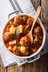 Meatballs tomato soup with vegetables and herbs close-up in a bowl. Vertical top view