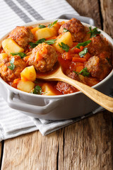 Freshly made tomato soup with meatballs and vegetables close-up in a pot. vertical