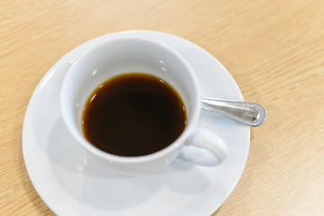 cup of hot coffee and spoon on wooden table in meeting room - coffee break