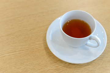 cup of hot tea and spoon on wooden table in meeting room