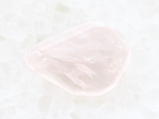 tumbled pink quartz gemstone on white marble