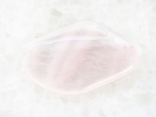 tumbled pink quartz gemstone on white marble