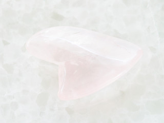 polished rose quartz stone in heart shape on white