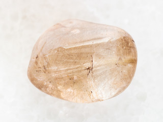 tumbled Rutilated Quartz gemstone on white marble