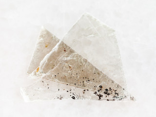 raw muscovite mica lamina on white marble