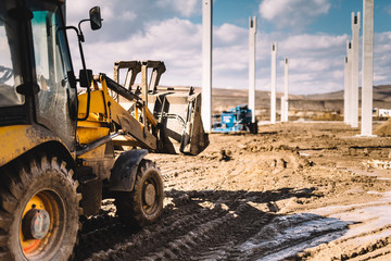 close up details of massive heavy duty machinery, industrial backhoe loader with excavator on construction site