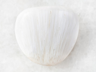 tumbled Scolecite gemstone on white marble