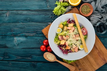 Caesar salad with salmon. Fresh vegetables. Healthy food. Top view. On a white wooden background. Copy space.