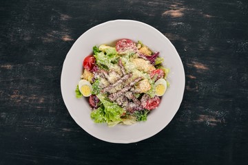 Caesar salad with beef. On a black wooden background. Top view. Copy space for your text.