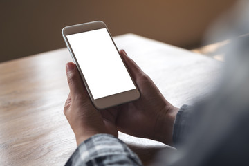 Mockup image of hands holding white mobile phone with blank desktop screen in cafe