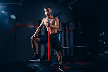 Fototapeta na wymiar Man fitness training with large and heavy tire hits hammer. Concept workout, cross strength training